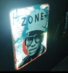 Zone de Mendo — street art sur panneau routier réfléchissant et jeu de lumière