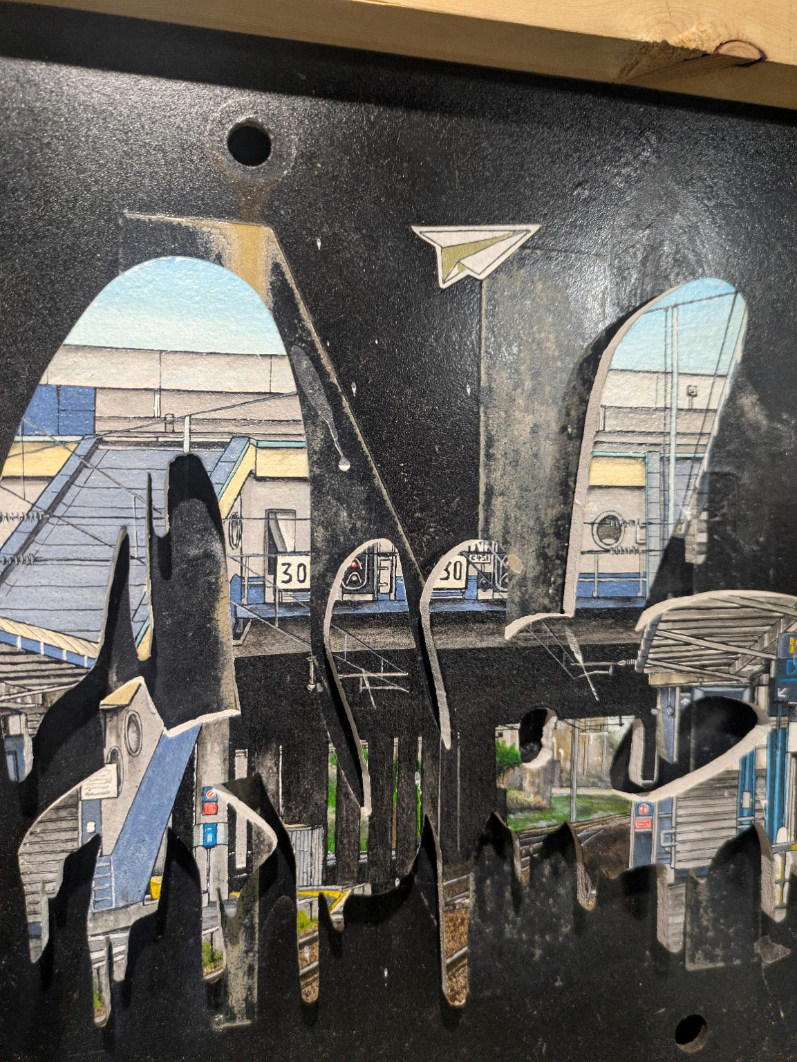 Gros plan sur le graffiti découpé, la gare de Calais et la patine du panneau SNCF